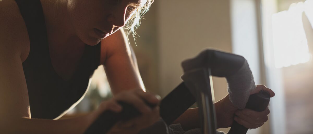 Exercise bike - mood picture of woman on exercise bike - it is worth it.